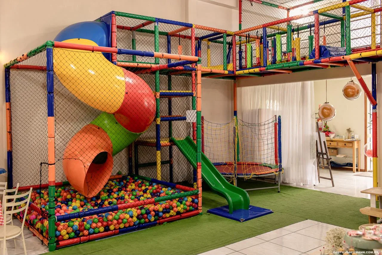 Brinquedão colorido com piscina de bolinhas, escorregador em espiral e cama elástica sobre grama sintética