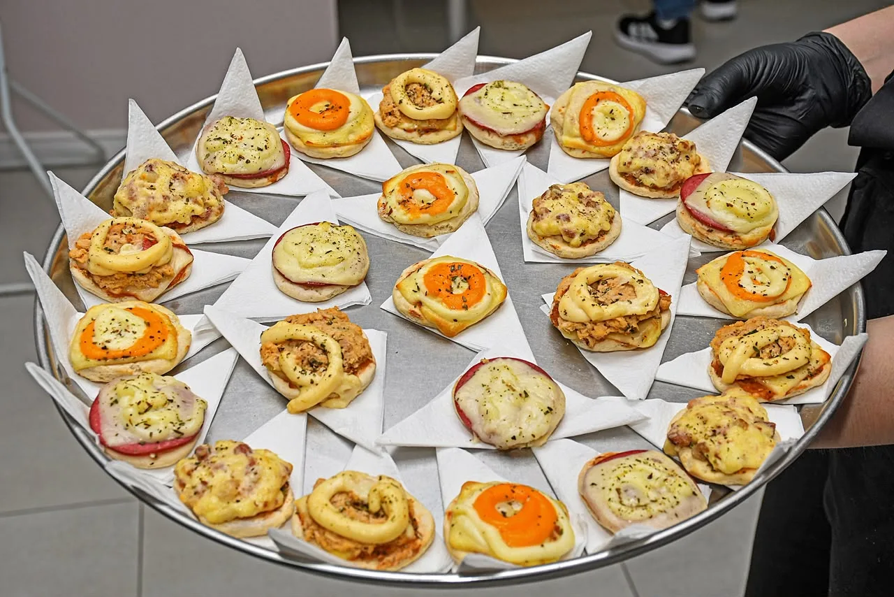 Bandeja redonda com mini pizzas variadas, cada uma sobre um guardanapo de papel