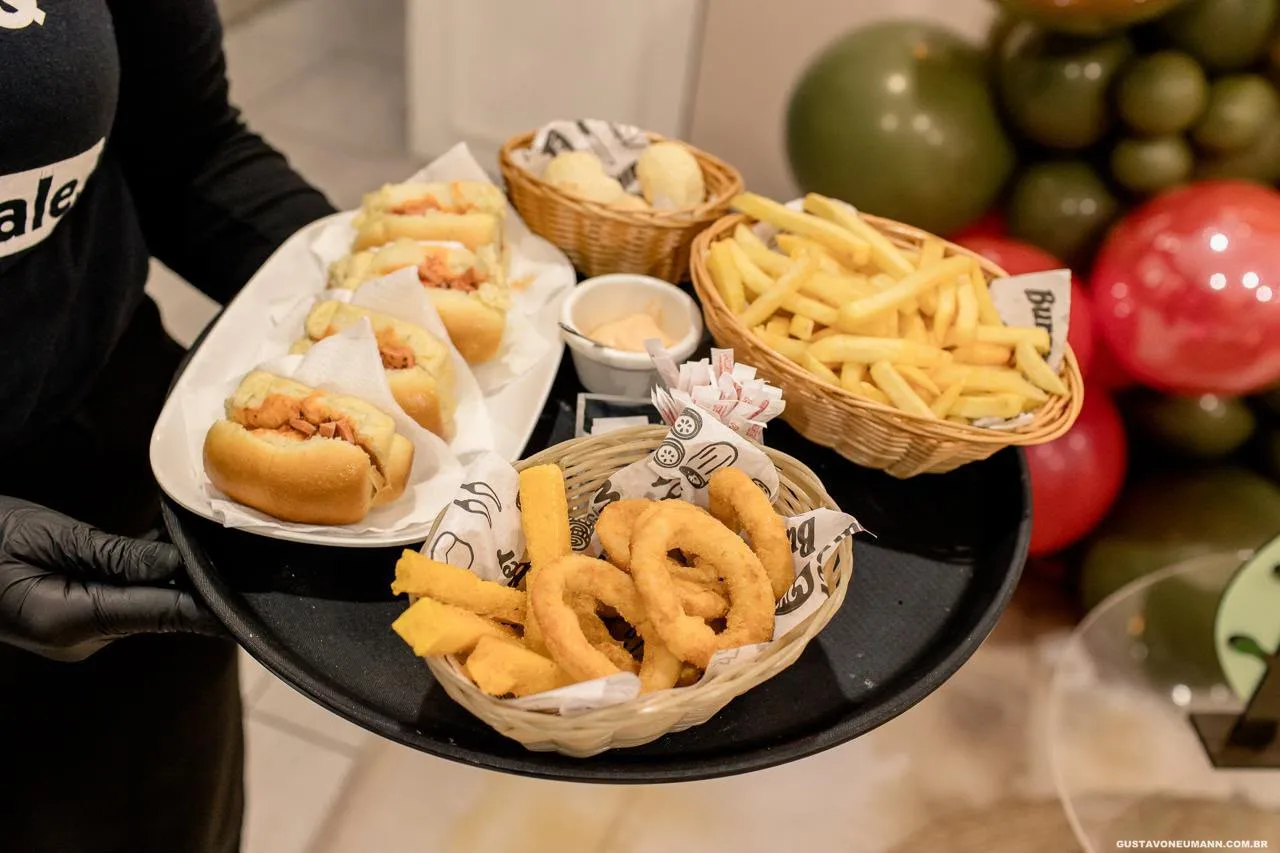 Bandeja com cachorro-quente, cesto de batata frita, anéis de cebola e pão de queijo